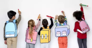 enfant en train d'écrire le long d'un mur blanc avec des sacs dessinés pour la garderie - inscriptions scolaires