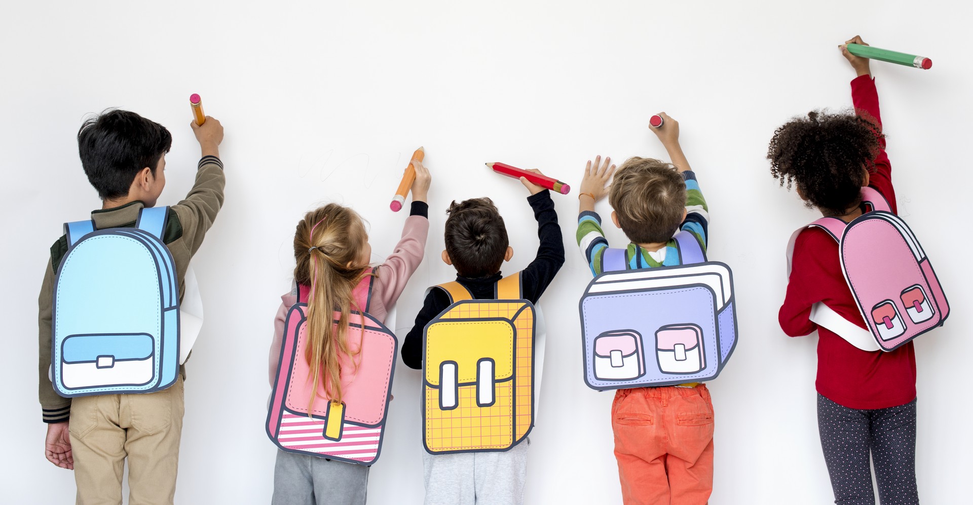 enfant en train d'écrire le long d'un mur blanc avec des sacs dessinés pour la garderie