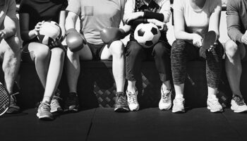 groupe de jeune assis sur un banc avec différents matériels de sport