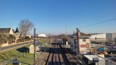 vue de la voie ferrée en surplomb des voies avec la gare du bourg sur la droite