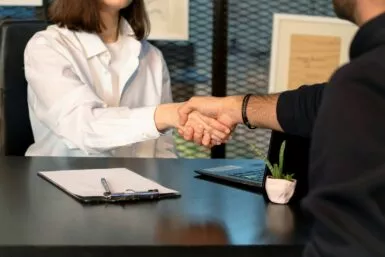 un homme et une femme se serrant la main devant un ordinateur portable pour représentant le service social