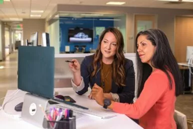deux femmes assises à une table regardant un écran d'ordinateur pour illustrer France Services