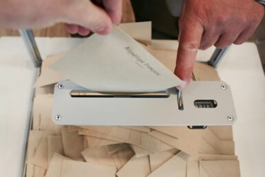 Personne en train de déposer une enveloppe dans une urne de vote suite à son inscription sur la liste électorale