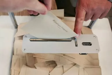 Personne en train de déposer une enveloppe dans une urne de vote suite à son inscription sur les listes électorales