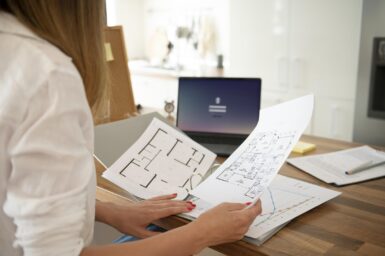 personne consultant un plan d'urbanisme avec un ordinateur devant elle