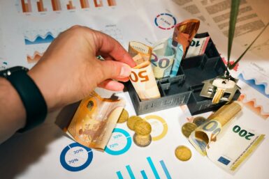 A person putting money into a miniature model house